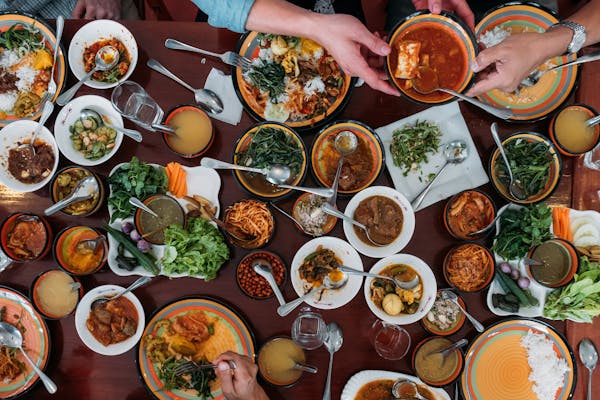 a group of people sitting at a table with many plates of food