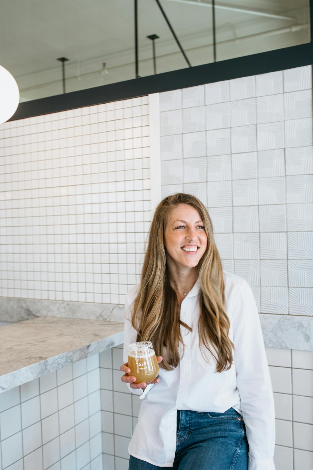 a woman standing in front of a tiled wall