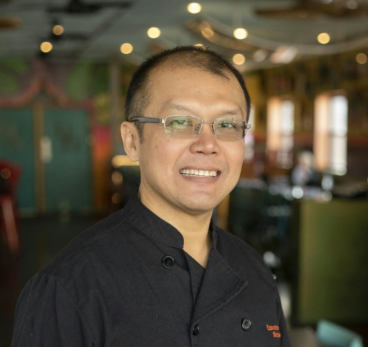 a man wearing glasses and smiling at the camera