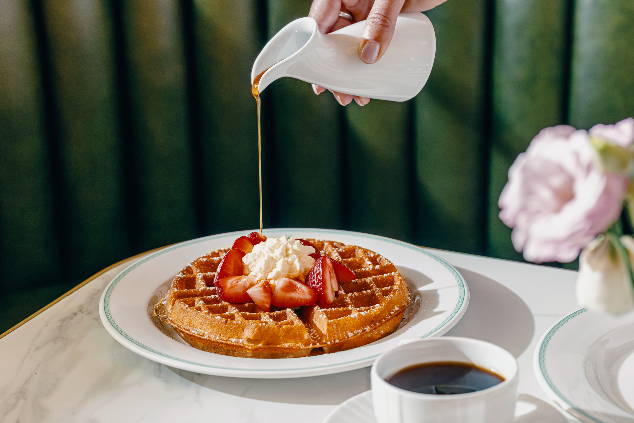 a person pouring syrup on a waffle