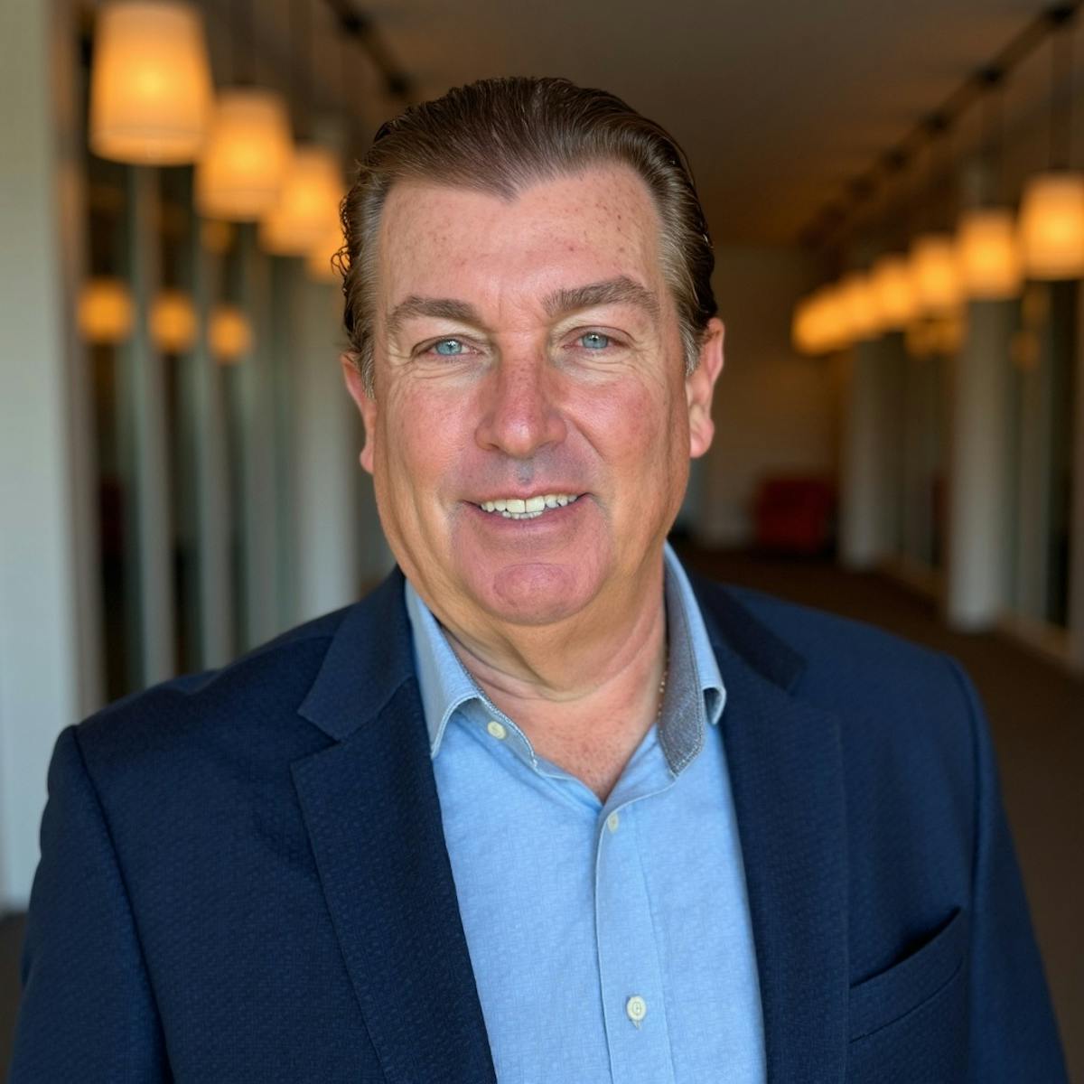 a man wearing a suit and tie smiling at the camera