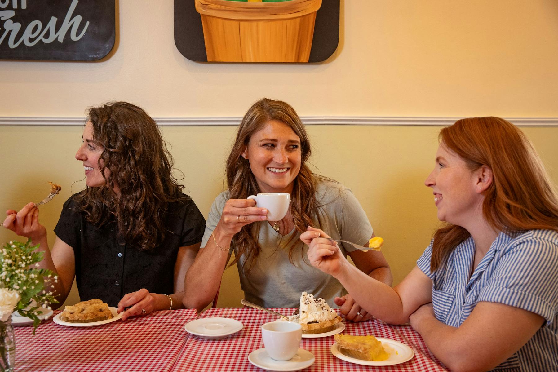 a group of women sitting at a table with food
