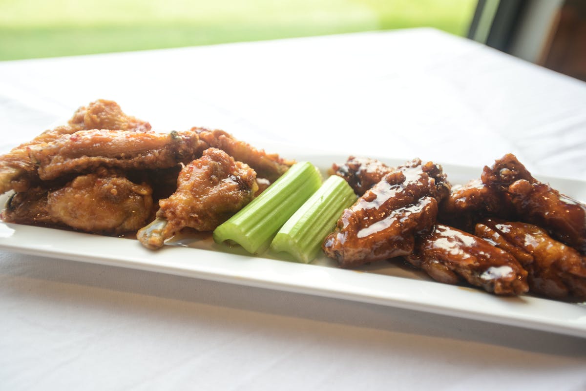 a white long rectangular plate topped with buffalo and BBQ wings