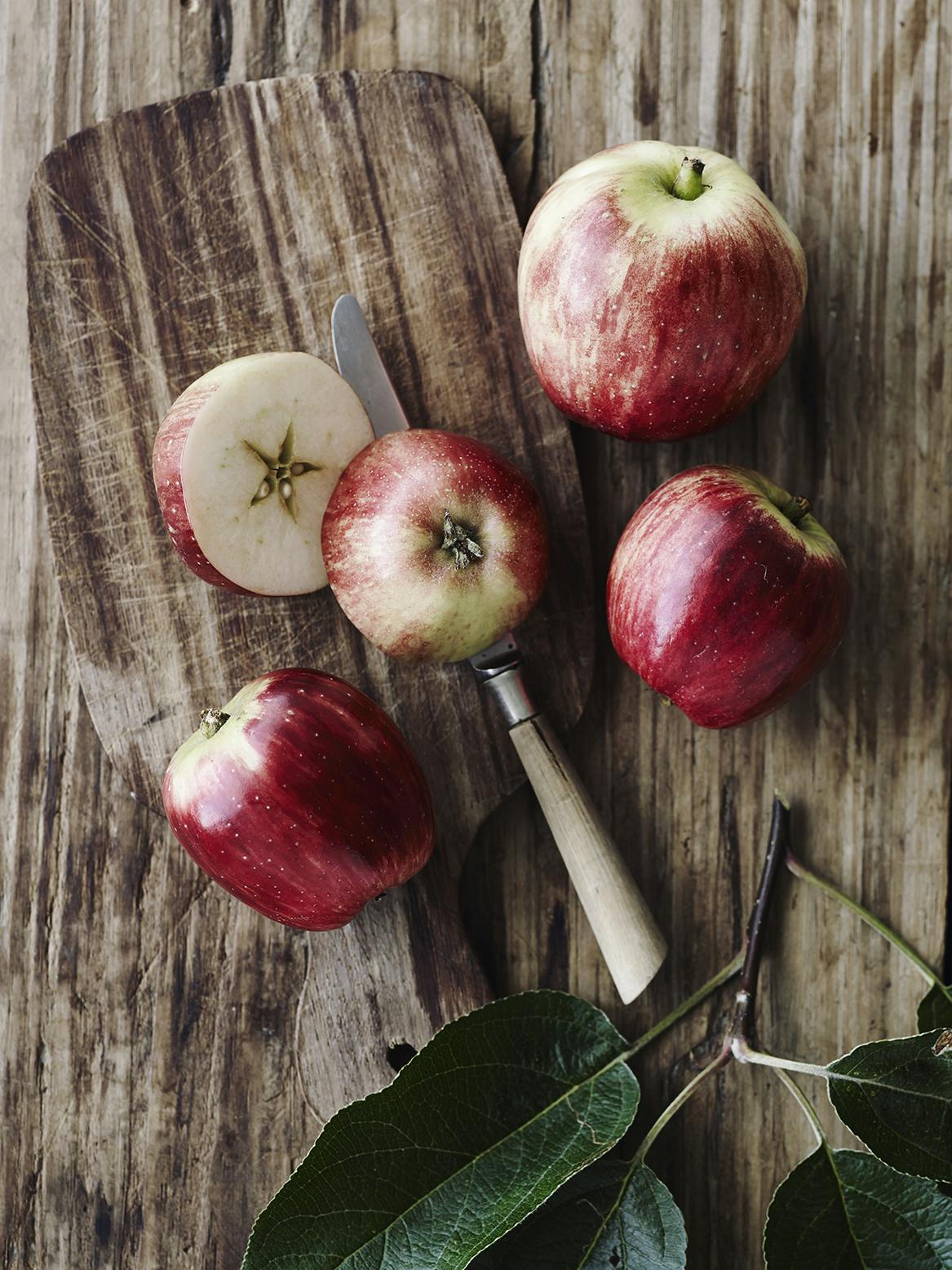 several apples and a knife on a board
