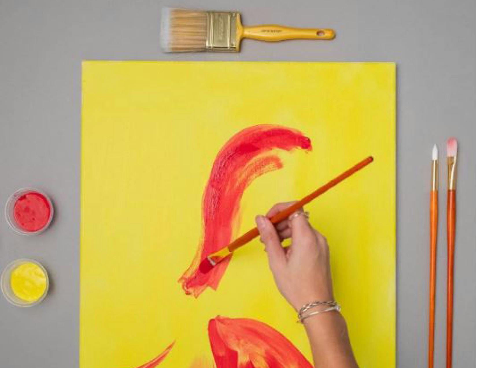 a person painting on a yellow paper