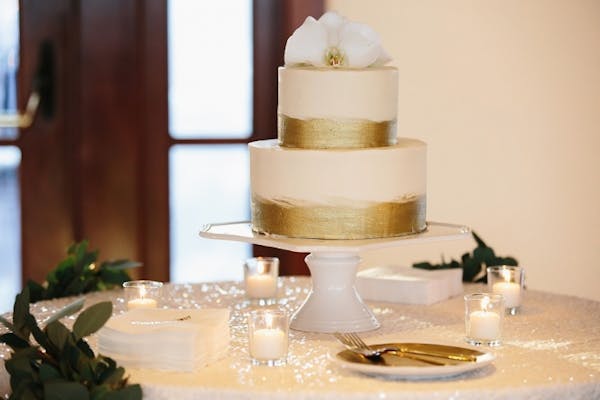 a two tier wedding cake with gold decorations