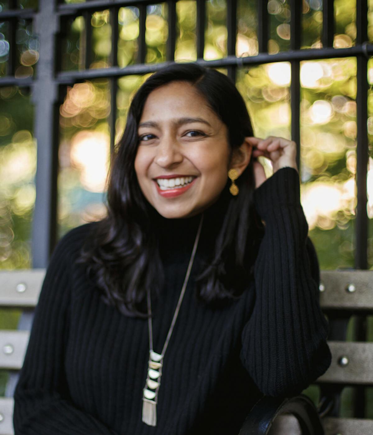 Priya Krishna sitting on a bench posing for the camera