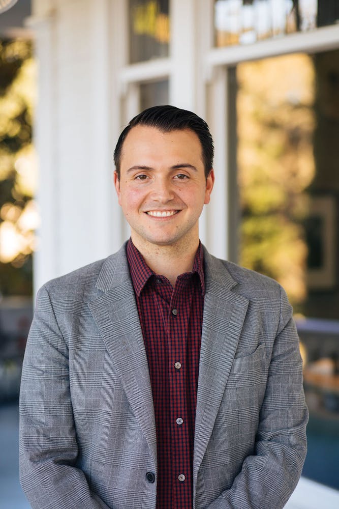 a man wearing a suit and tie smiling at the camera