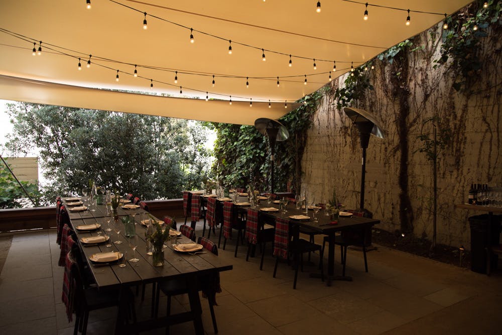 large tables set in the garden decorated with light bulbs on the ceiling