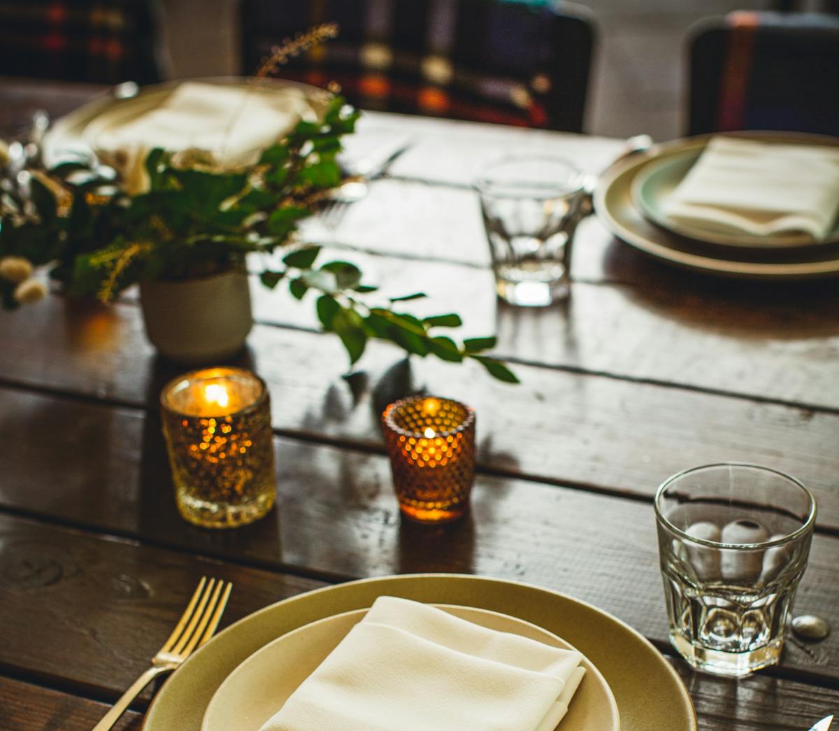 a table seat set with plates and a candle