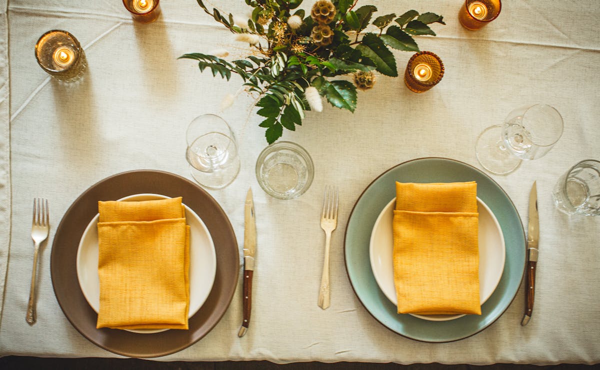 a table sit decorated with a yellow napkin on each plate
