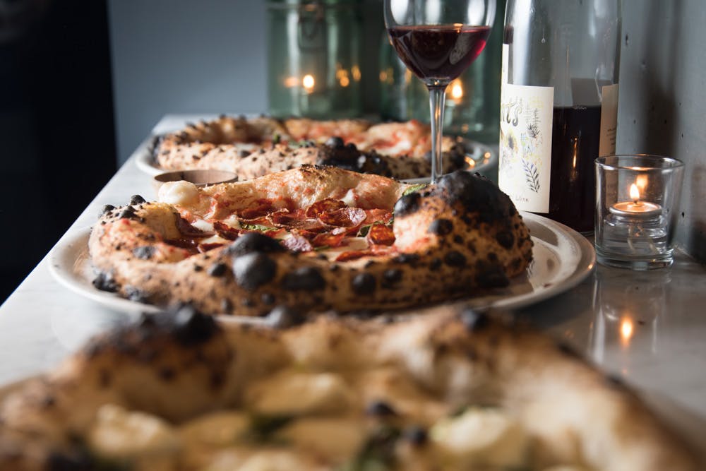 a close up of a plate of pizza and a glass of wine
