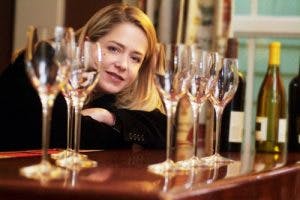 a woman sitting at a table with wine glasses