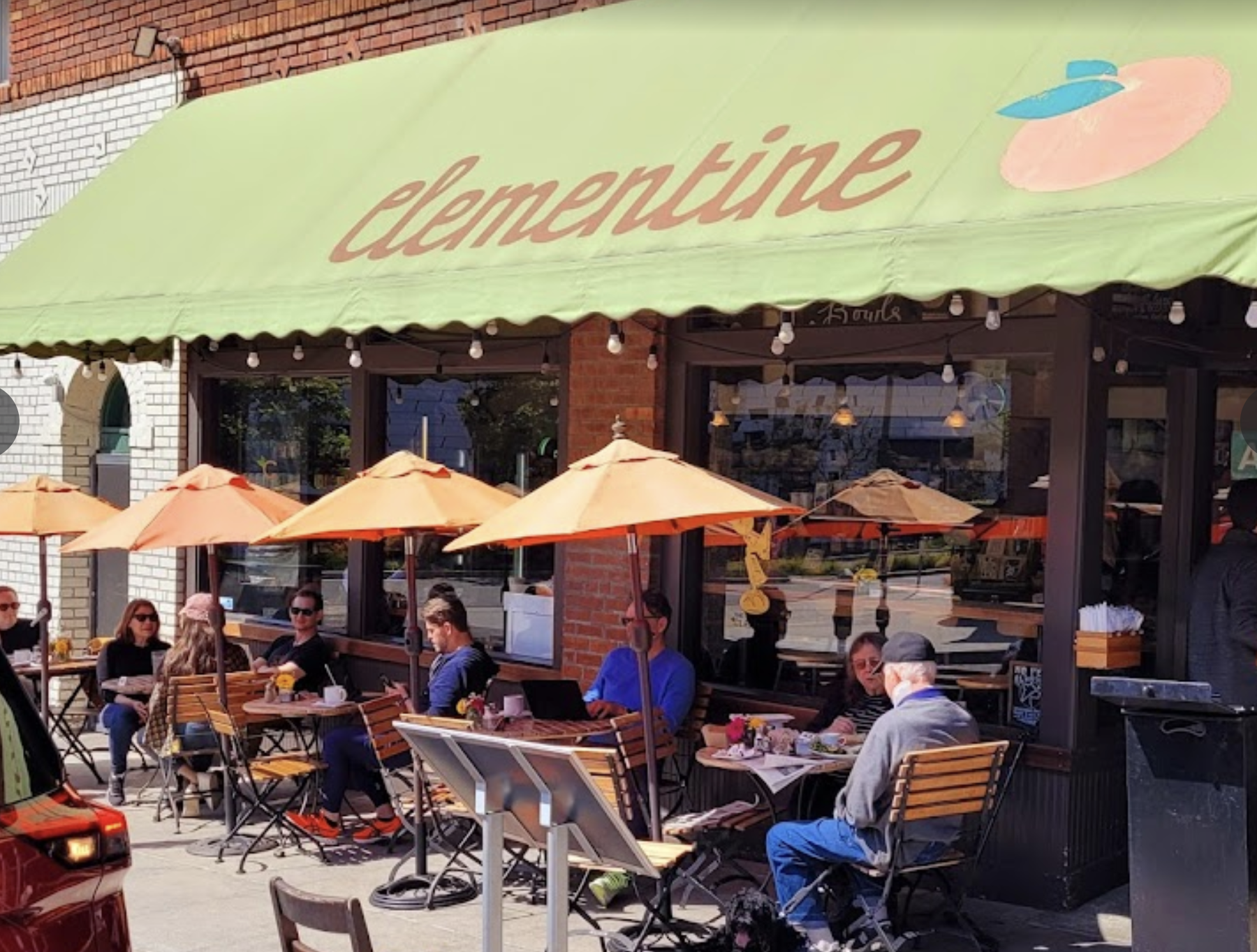 a group of people sitting at tables outside a restaurant