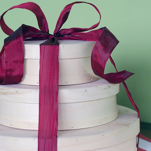 a stack of wooden gift boxes tied with red ribbon