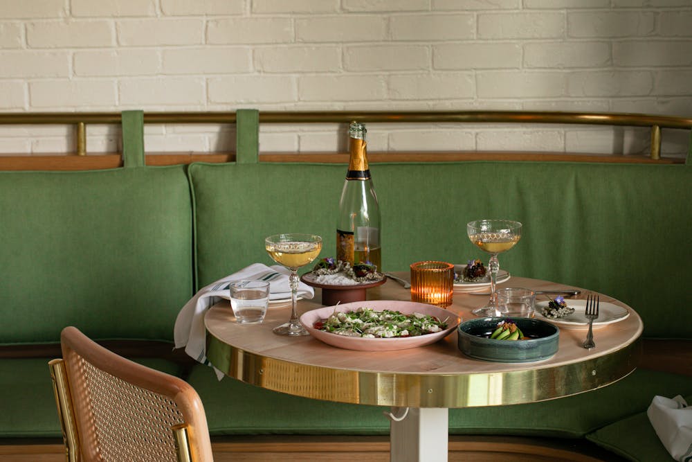 a green chair next to a glass of wine on a table