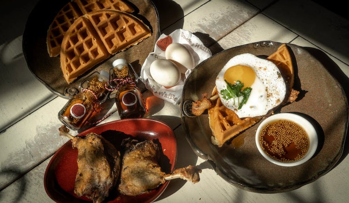 beautiful Duck & Waffle kit for two people available on Goldbelly including succulent duck confit leg, whole duck eggs, fluffy waffles and signature mustard maple syrup