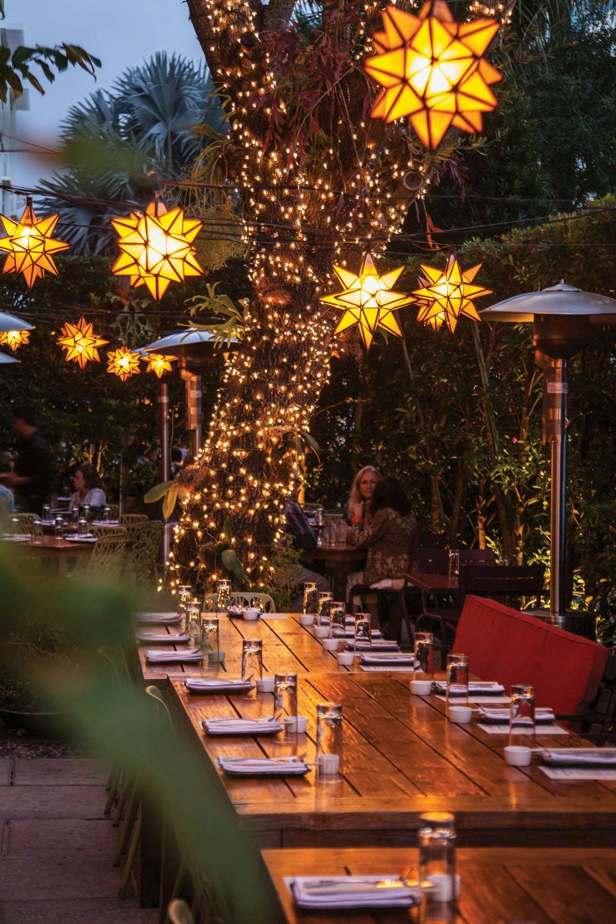 An outdoor table in SUGARCANE raw bar grill in Miami beneath a tree with white lights.