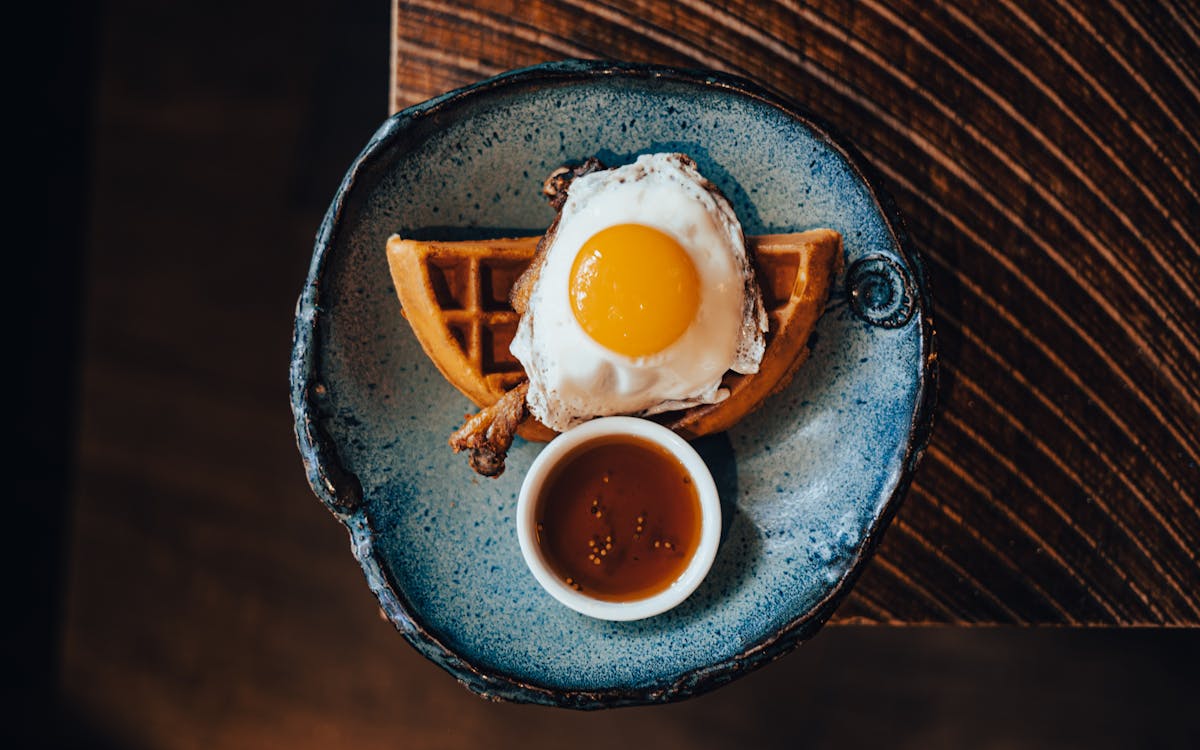 an egg on a plate next to a cup of coffee