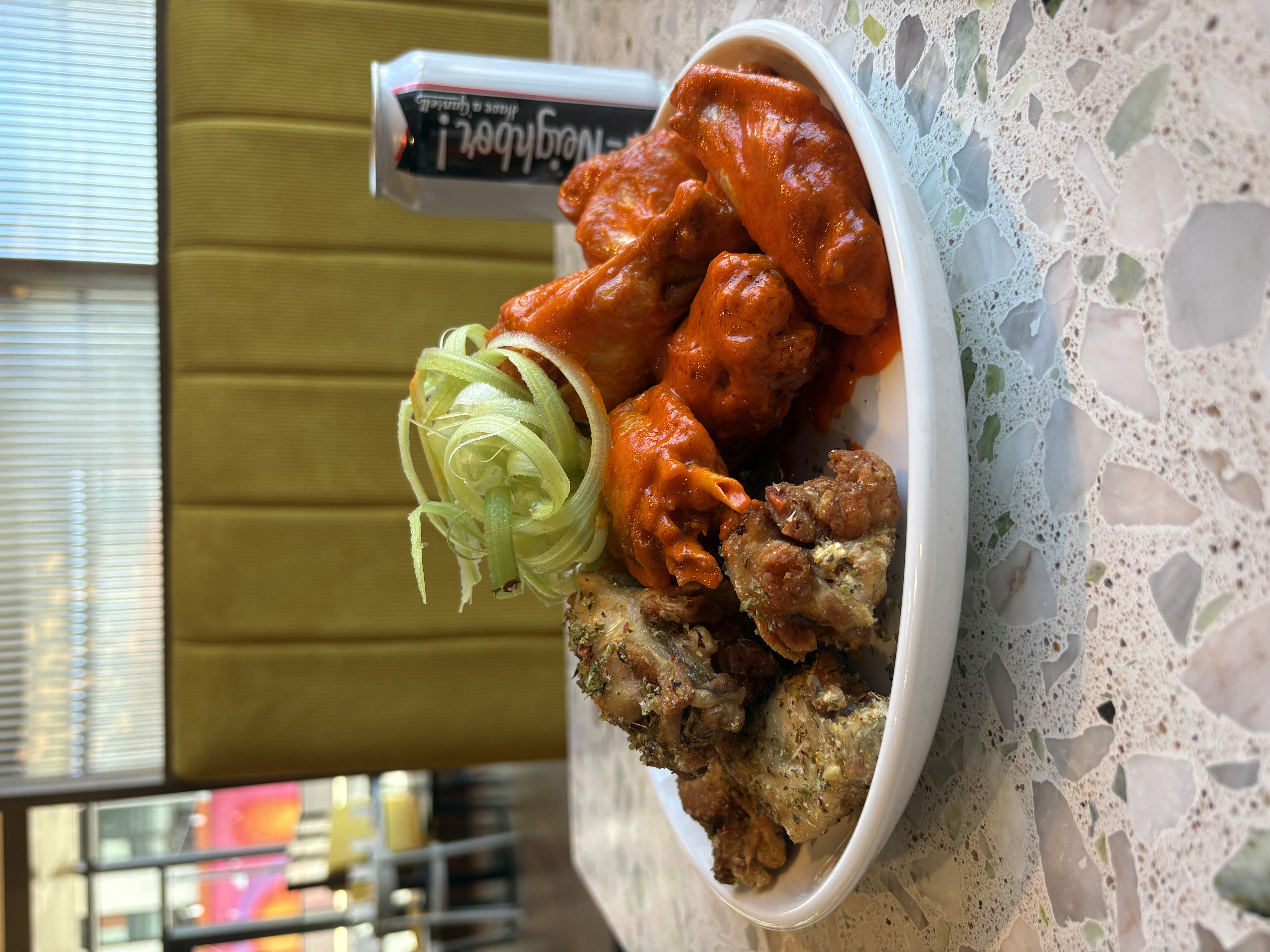 a plate of chicken wings and a can of beer
