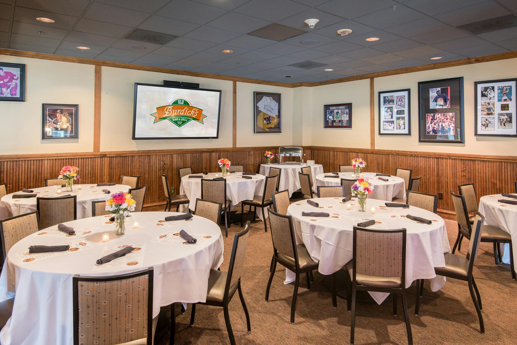 a large room filled with dining tables topped with white table cloths and glassware sided by chairs