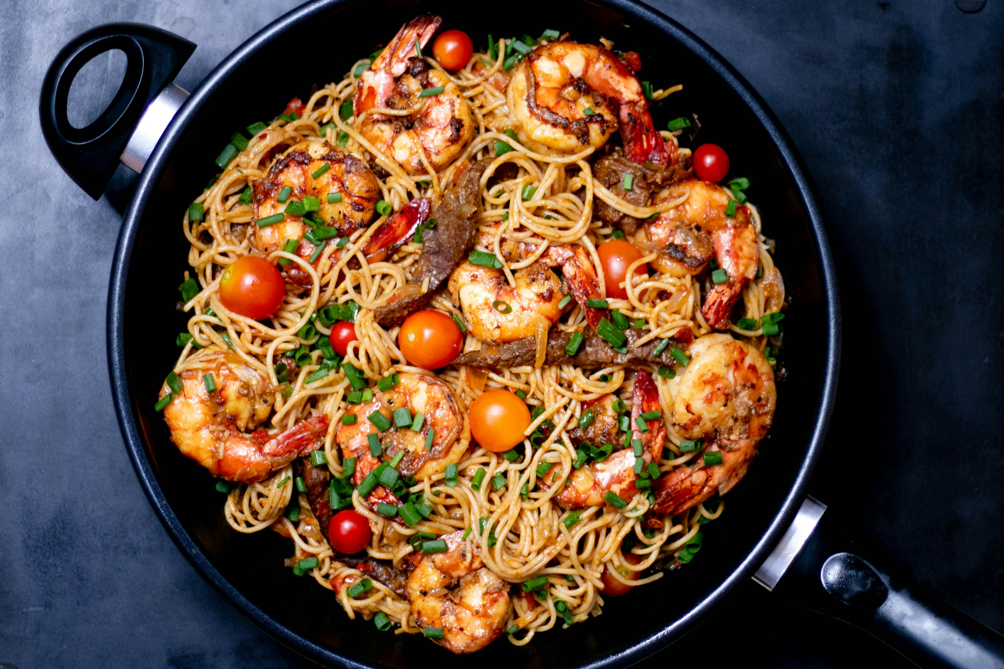 a bowl of pasta with shrimp and tomatoes
