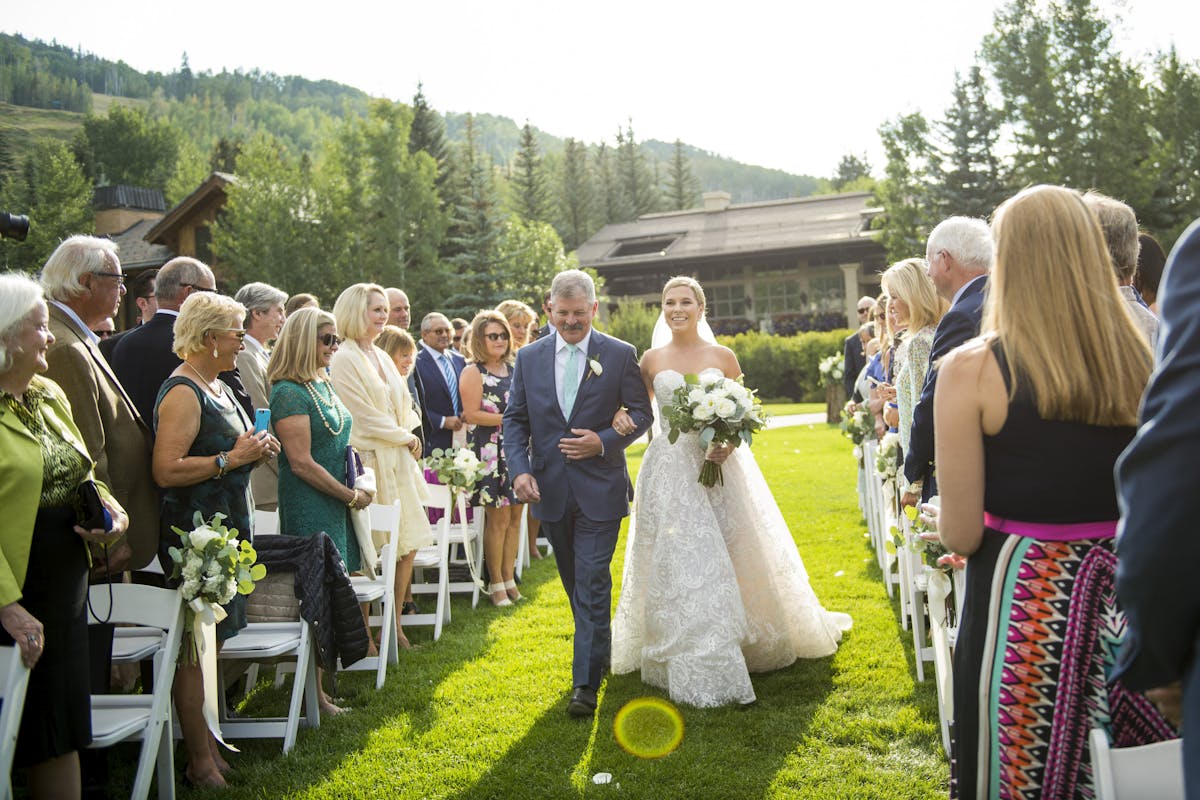 a group of peLarkspur Wedding Venue Vail Colorado Mountain Rehearsal, Welcome Reception Mountainside Patio Outdoor Reception Ceremony Lawnople that are standing in the grass