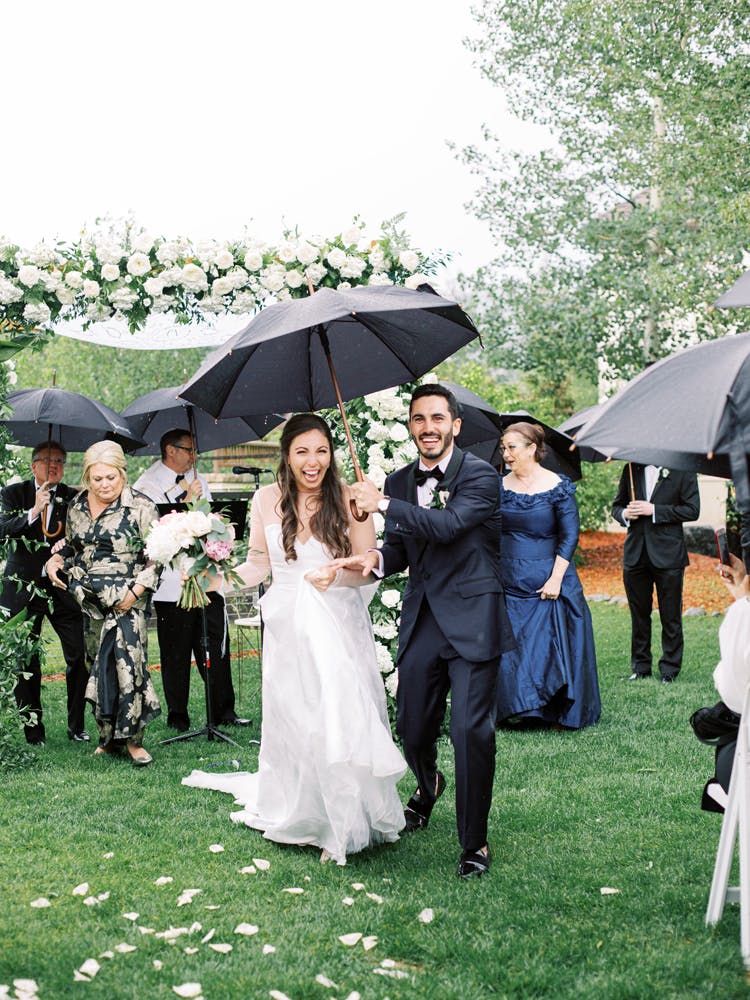 Larkspur Wedding Venue Vail Colorado Mountain Wedding a group of people standing in the rain holding an umbrella