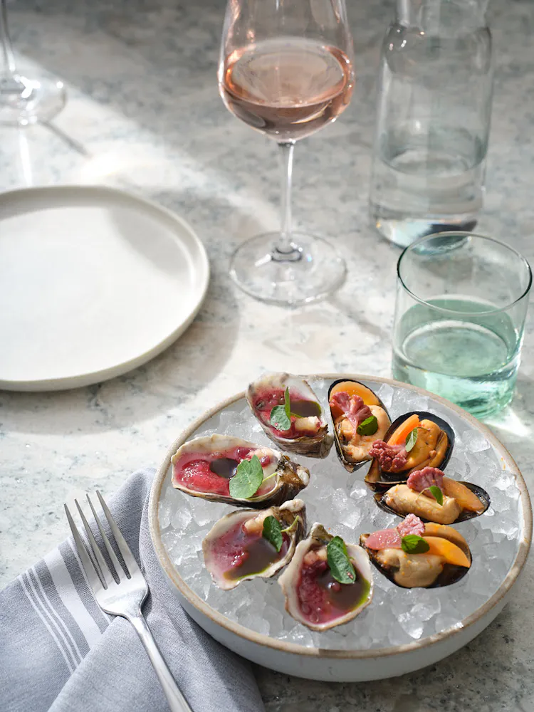 a plate of food on ice with a fork and glass of wine