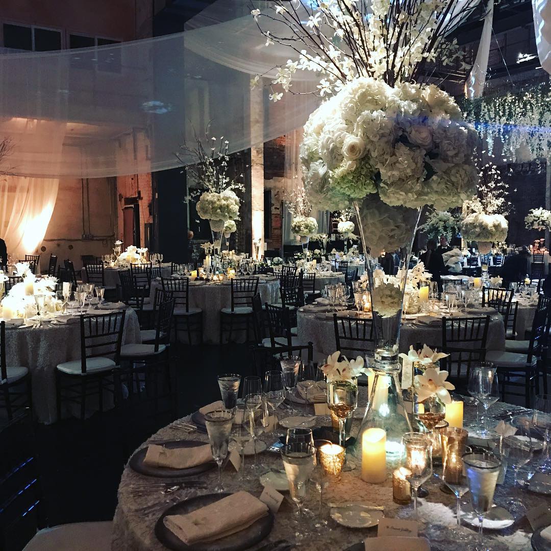 a large group of tables with white flowers and candles