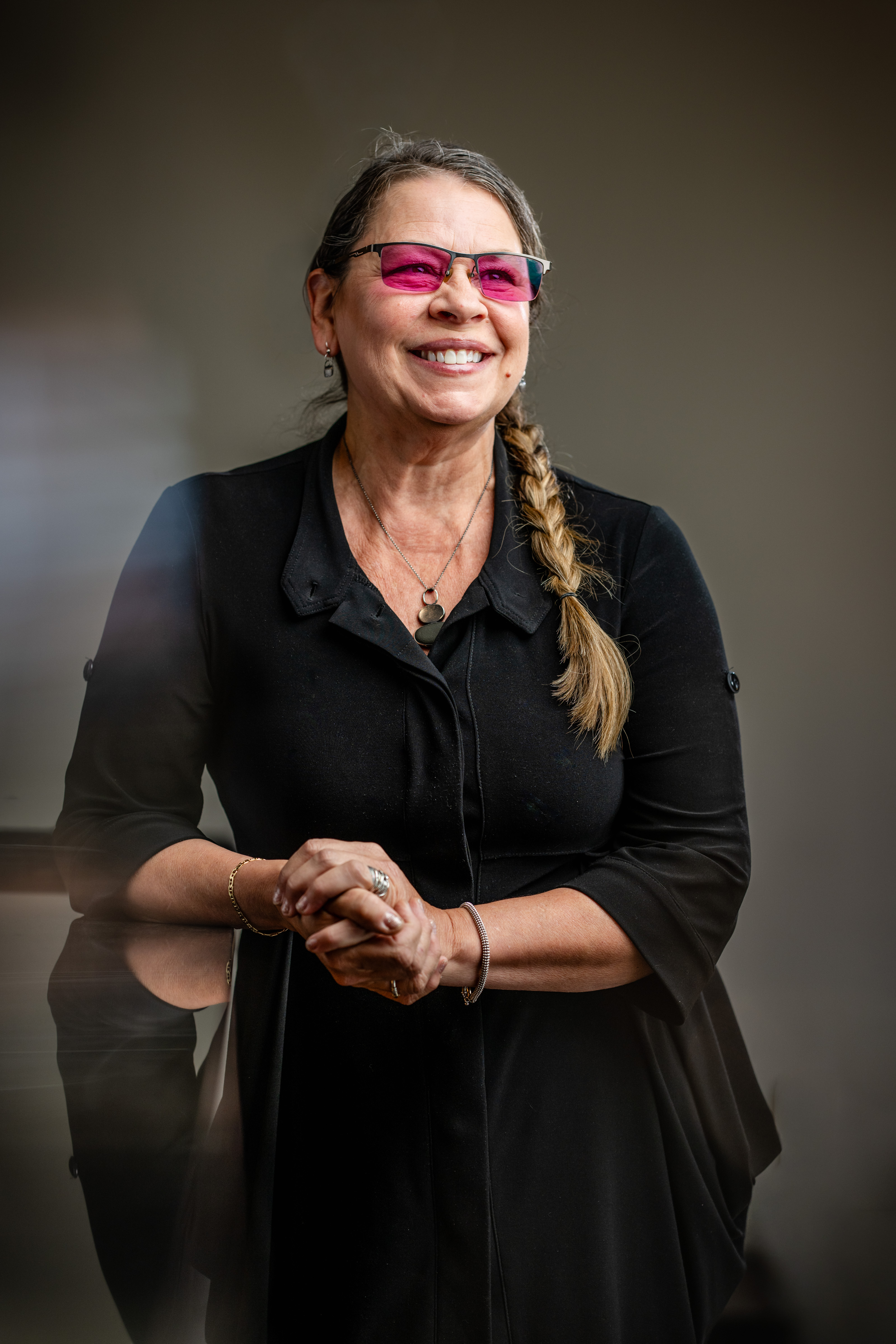 a woman in black shirt and pink glasses smiling