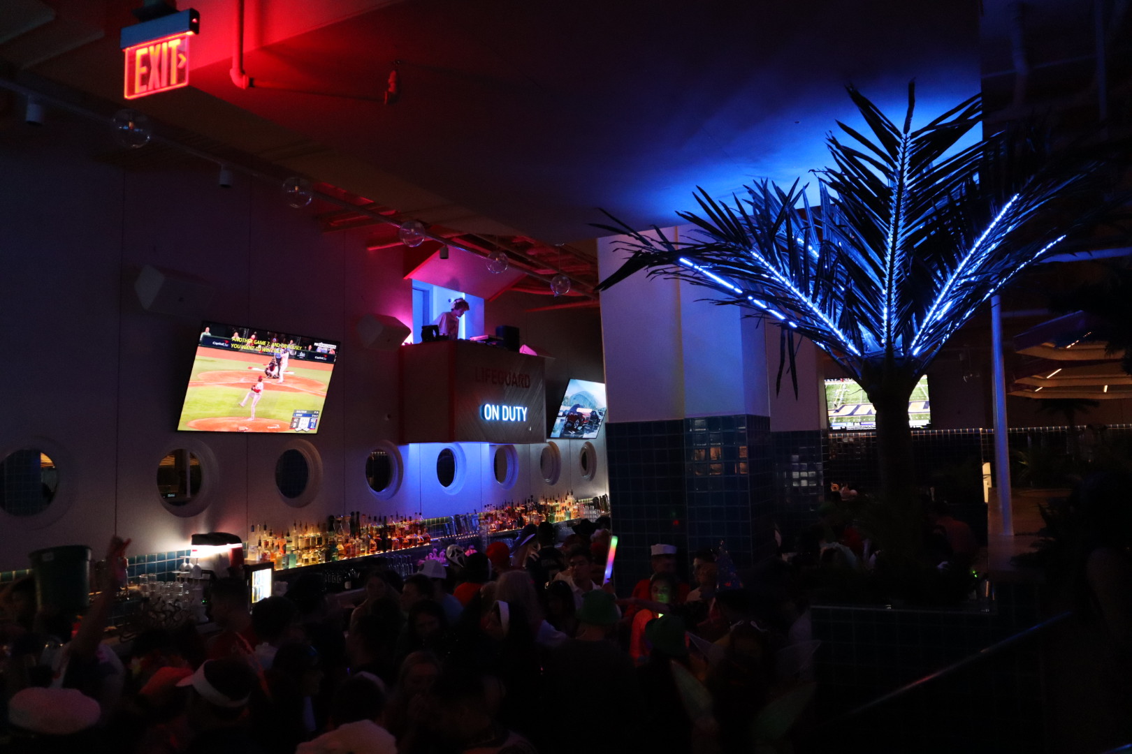 a group of people standing next to a christmas tree lit up at night