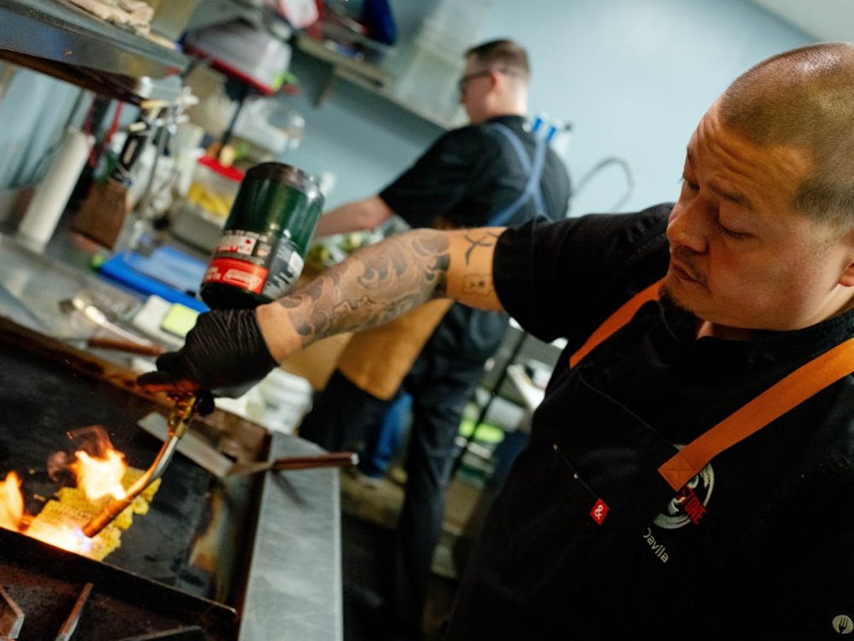 a man cooking hot dogs on a grill