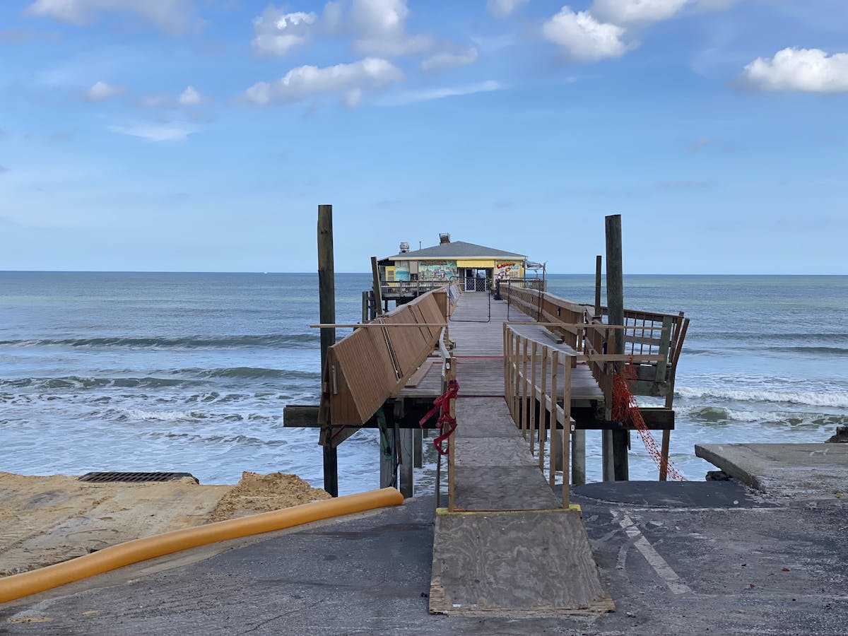 a beach with a pier in front of a body of water