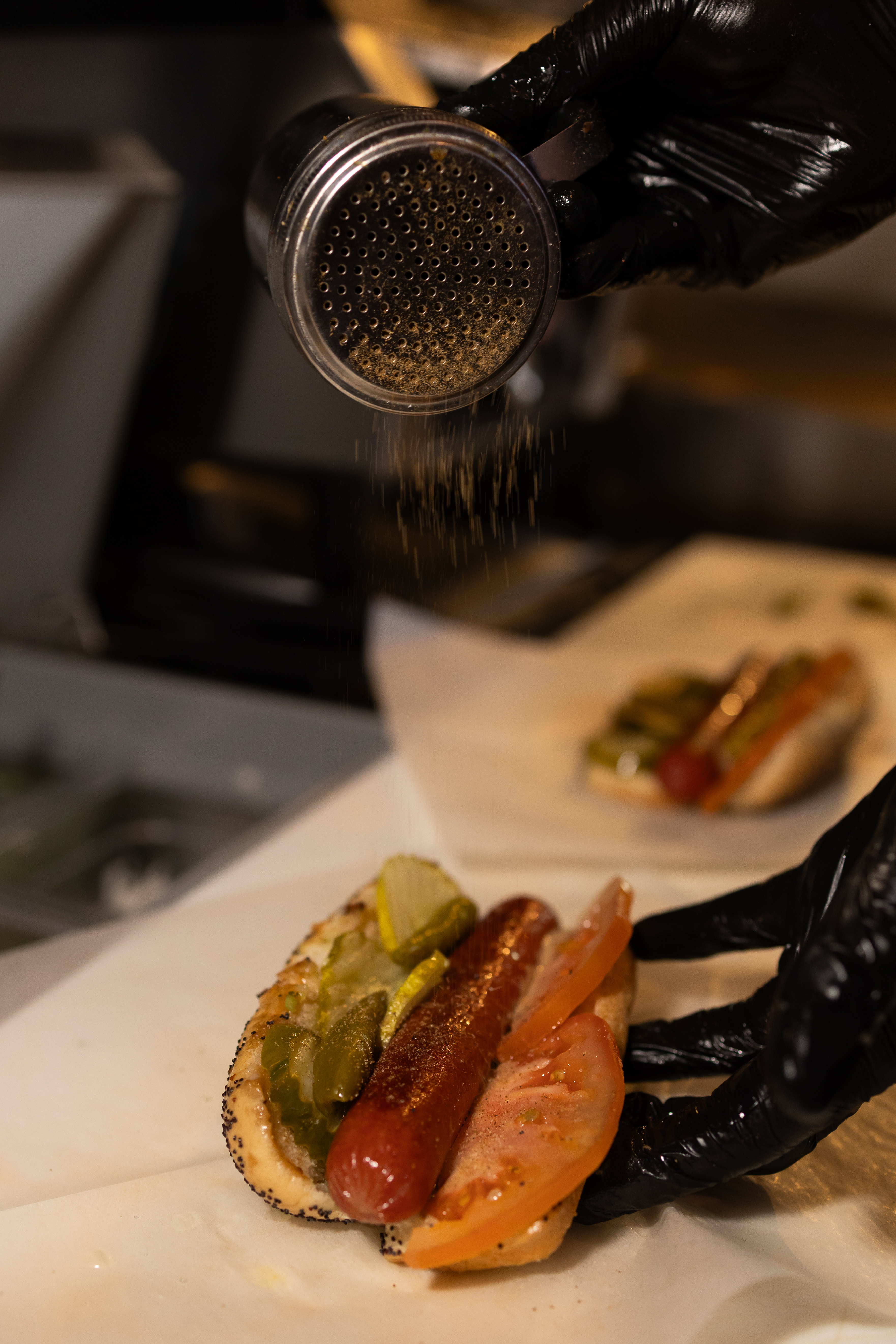 a person putting seasoning on a hot dog