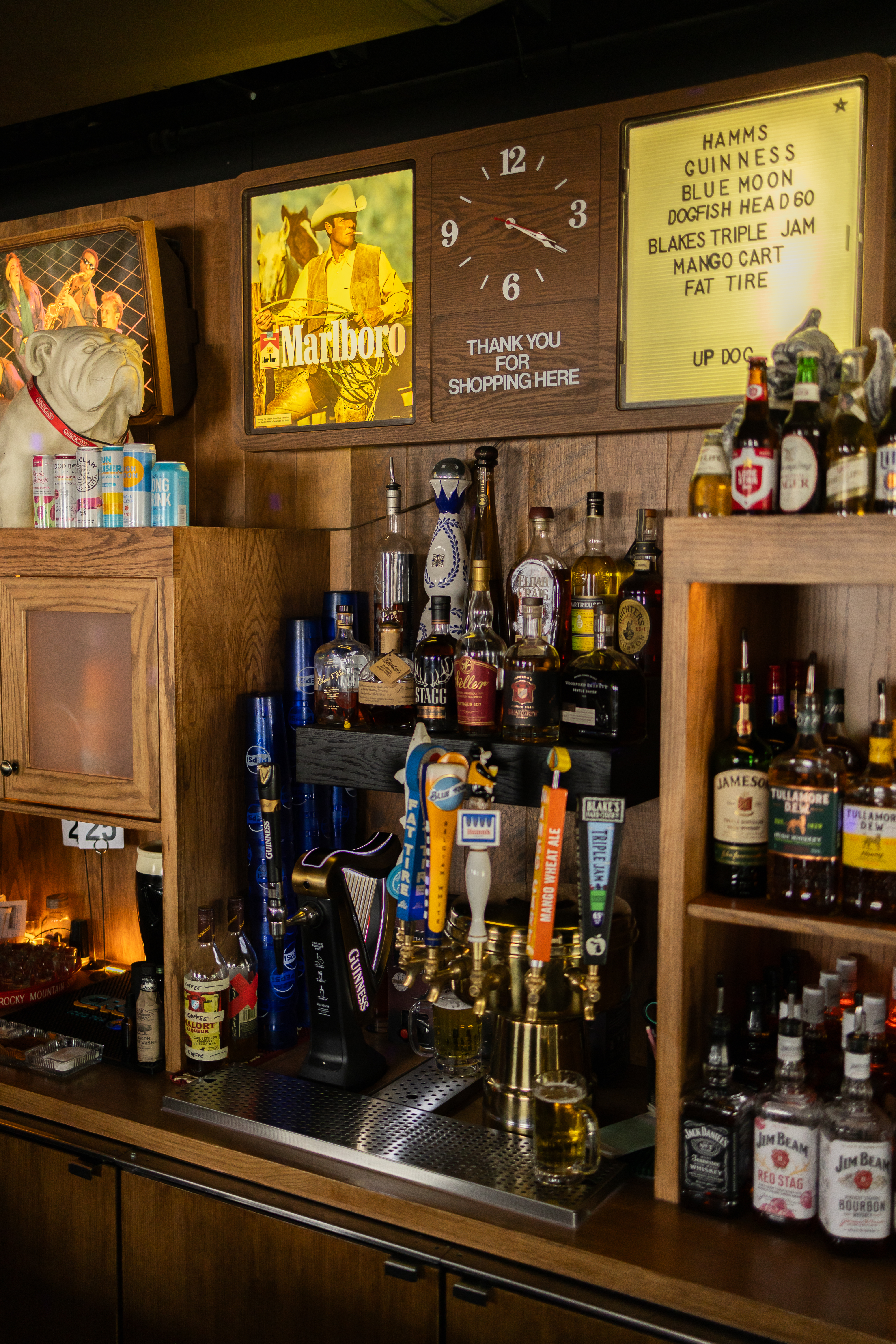 a shelf with bottles of alcohol and a clock
