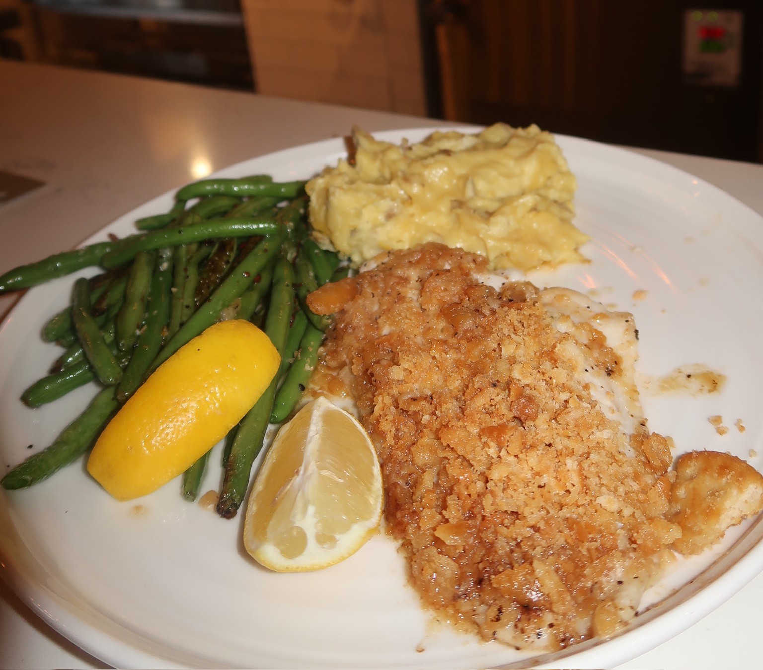 a plate of food with a lemon wedge and a side of green beans
