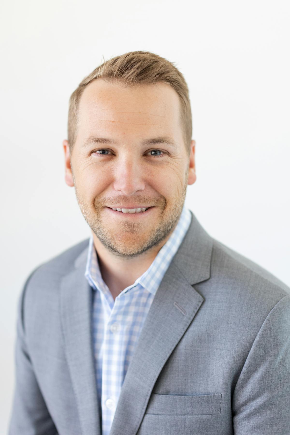 a man wearing a suit and tie smiling and looking at the camera