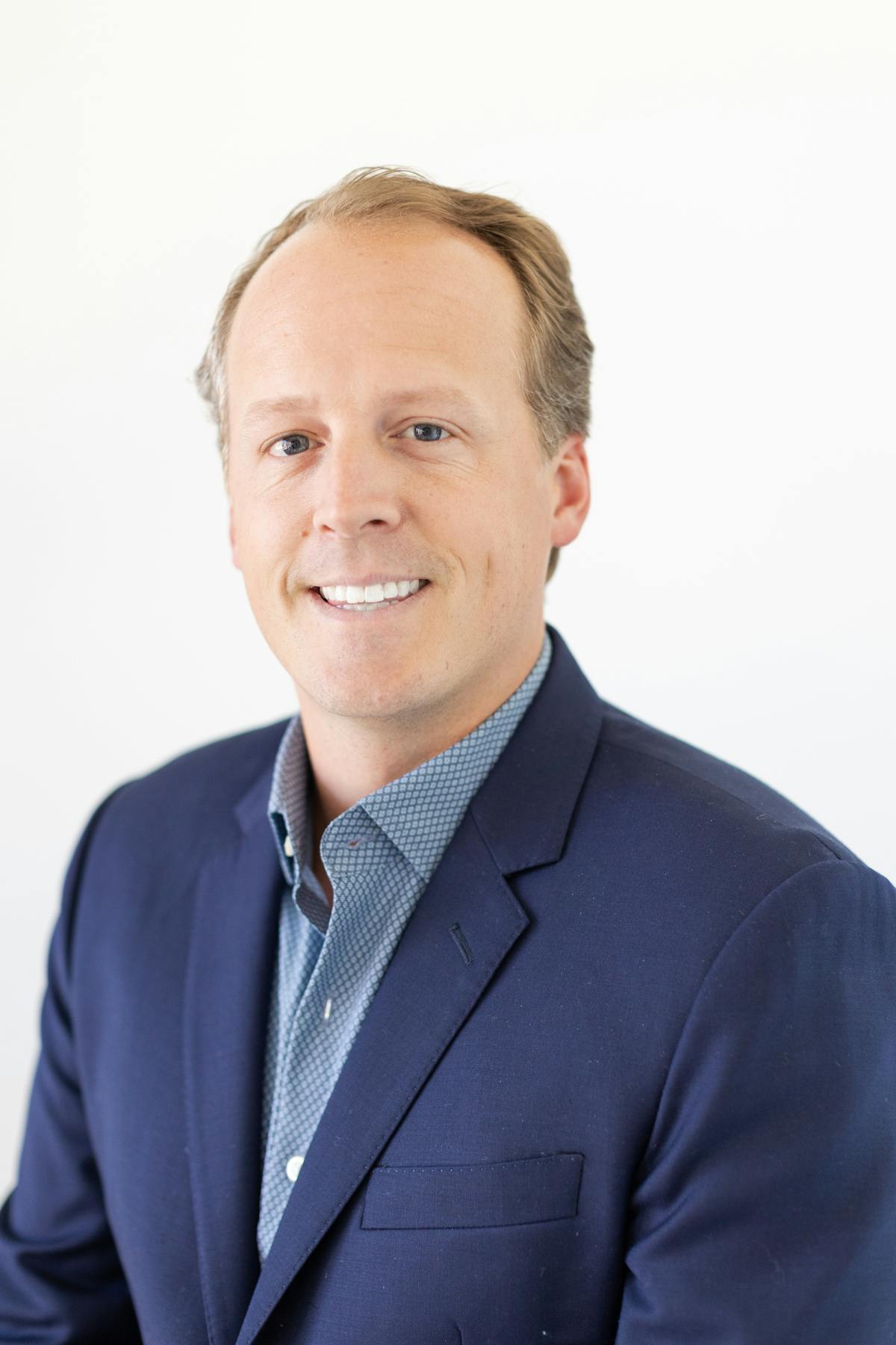 a man wearing a suit and tie smiling at the camera