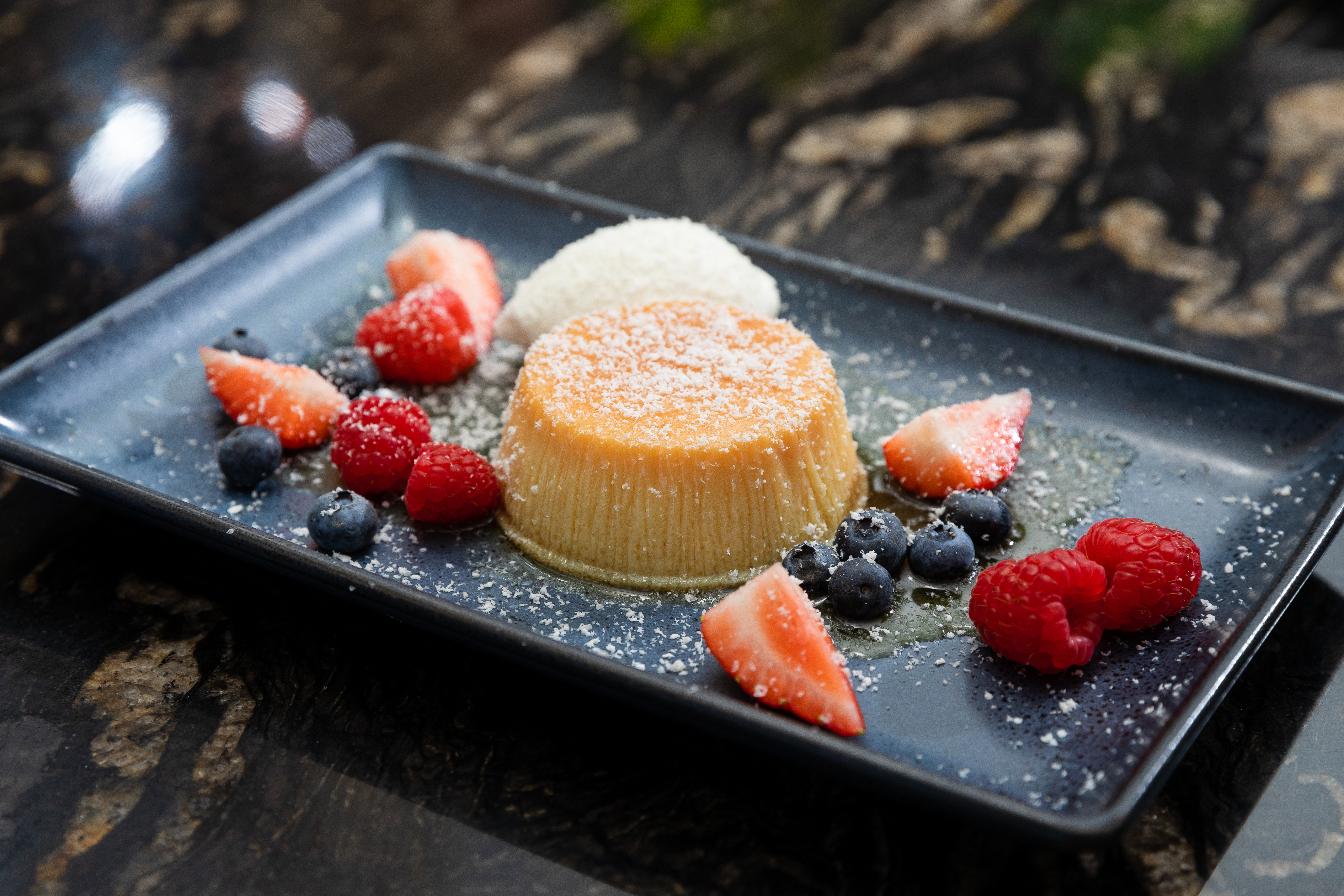 plate of flan dessert with strawberries and blueberries