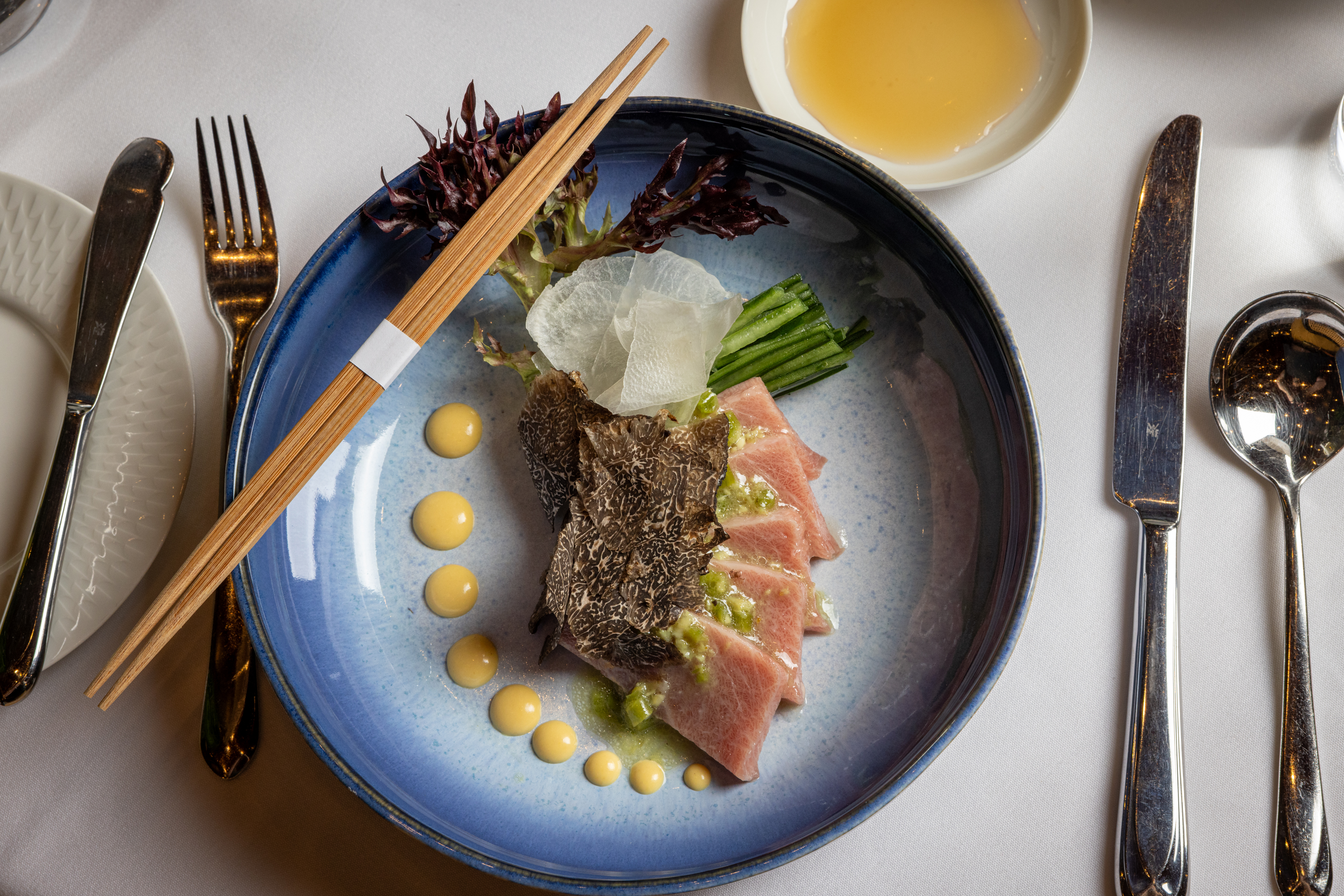 a plate of food with chopsticks and a bowl of liquid