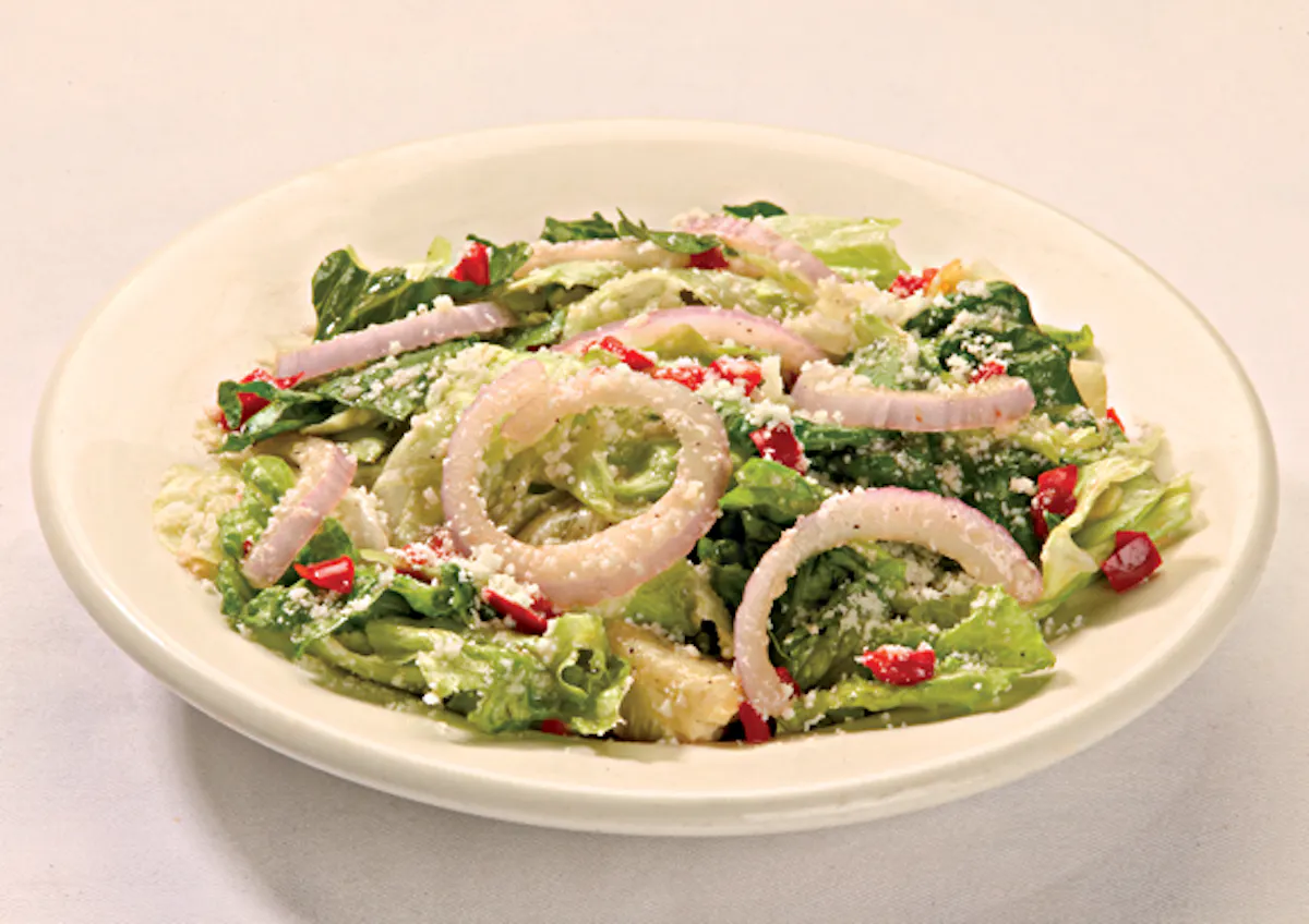 a bowl of salad topped with croutons and onions