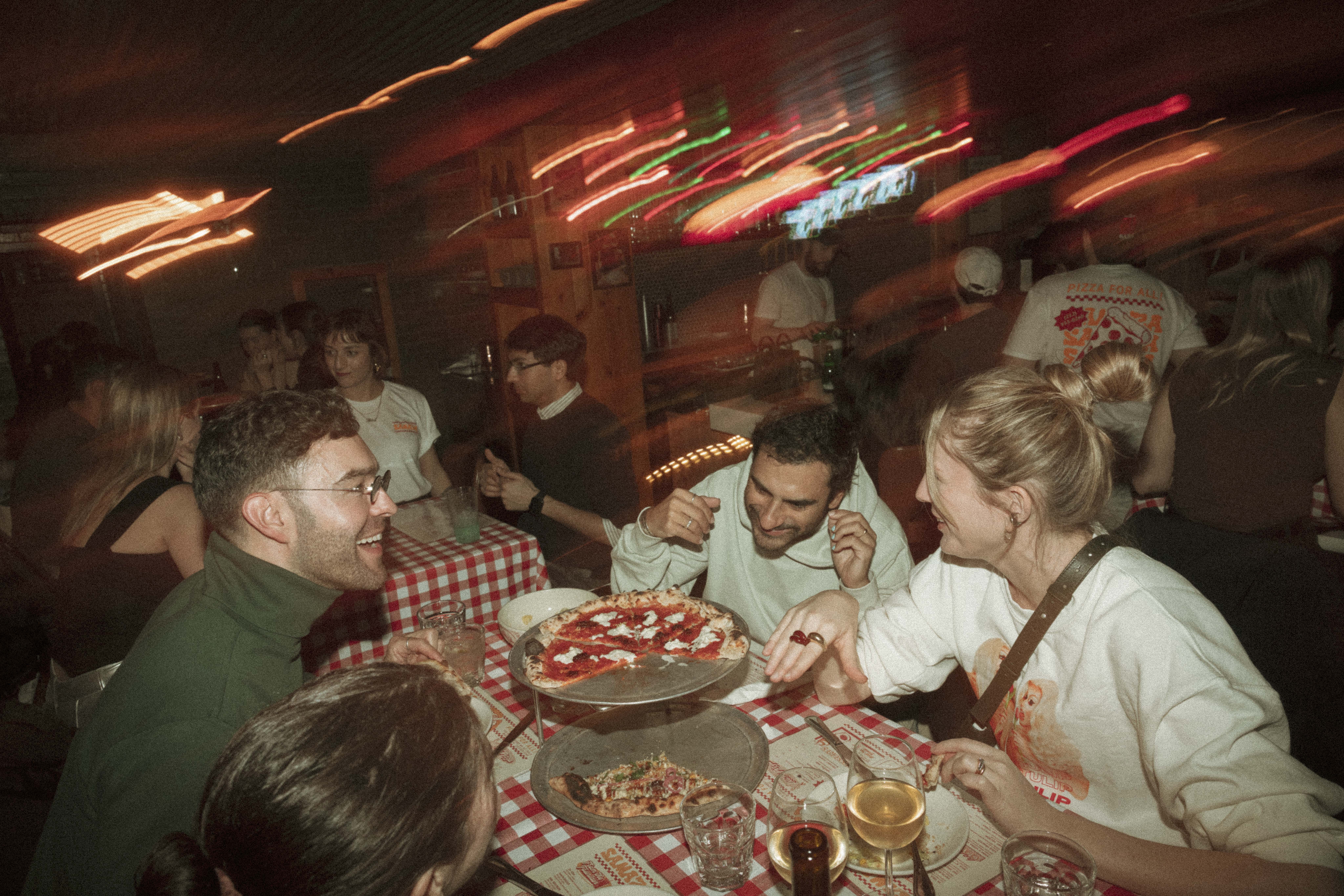 a group of people eating pizza at a table