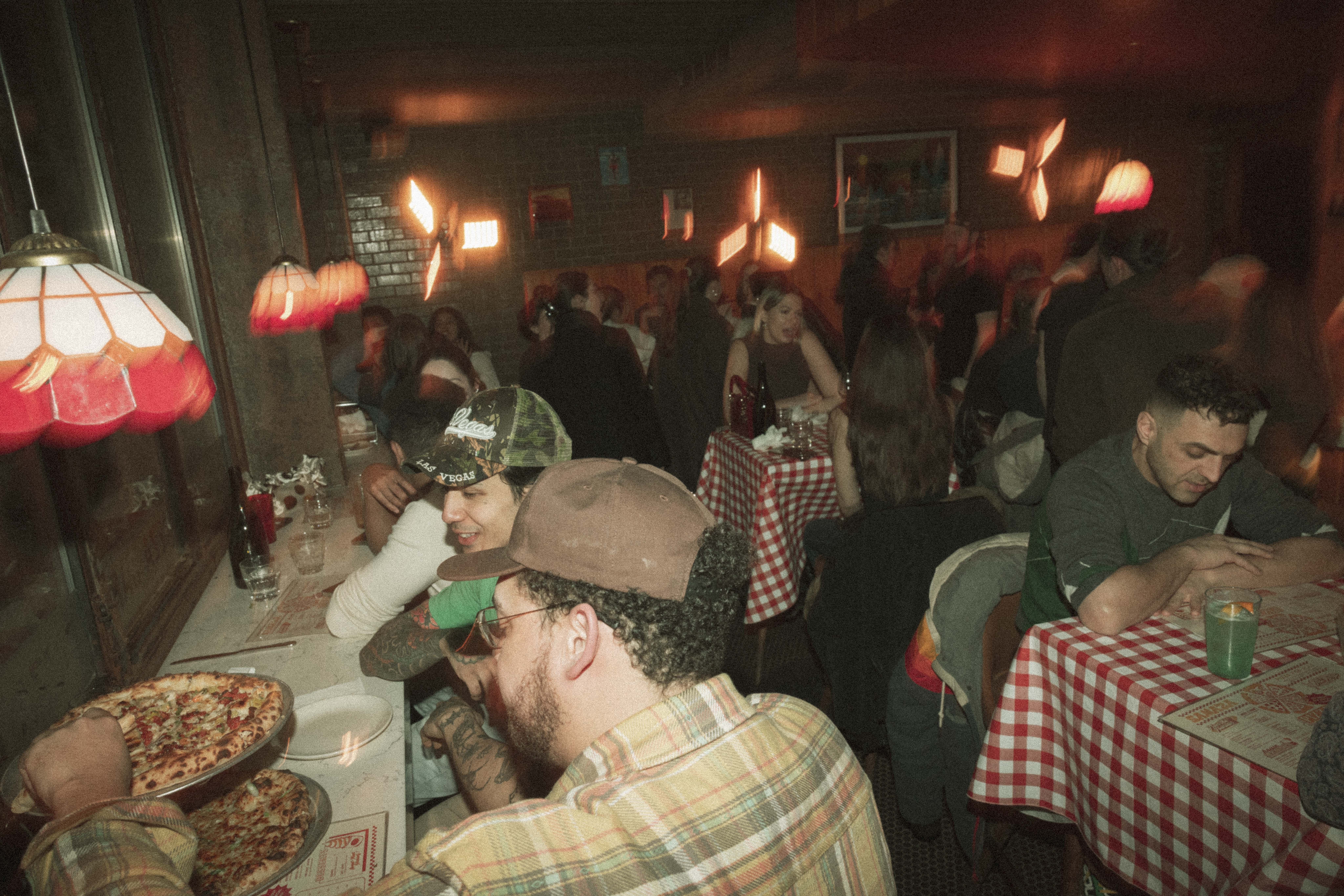 a group of people sitting at tables with pizzas