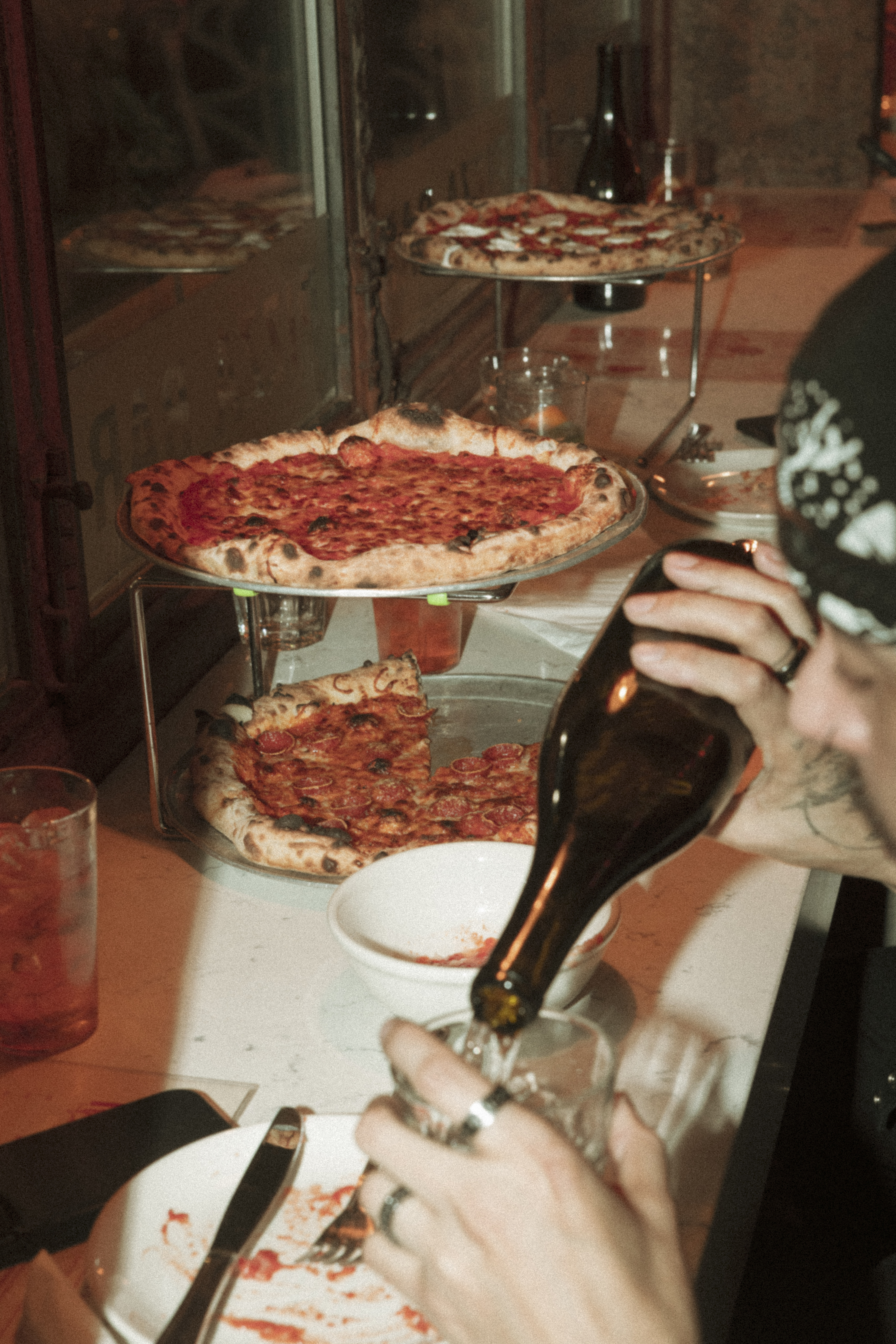 a person pouring a bottle of wine into a pizza