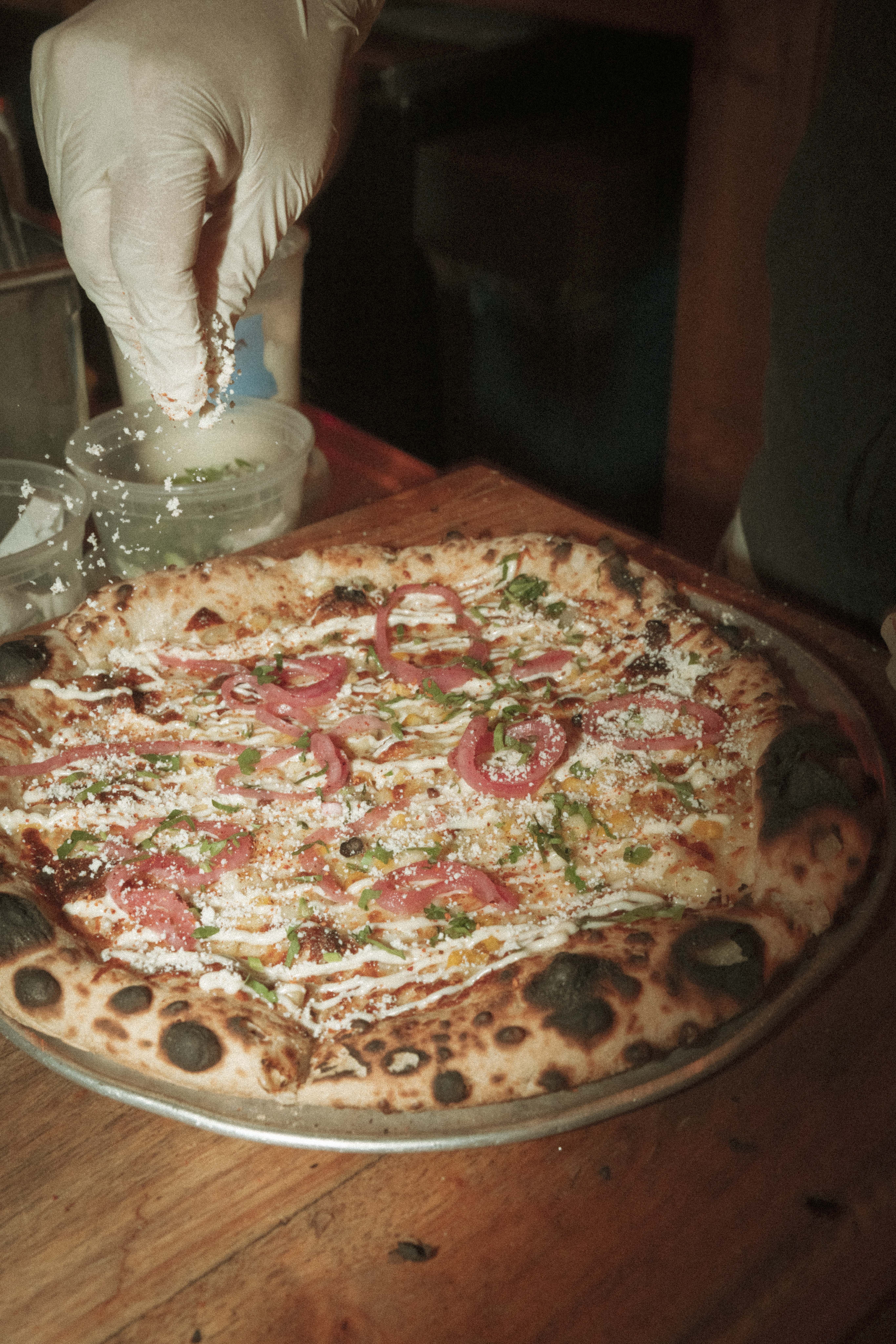 a person sprinkling salt on a pizza