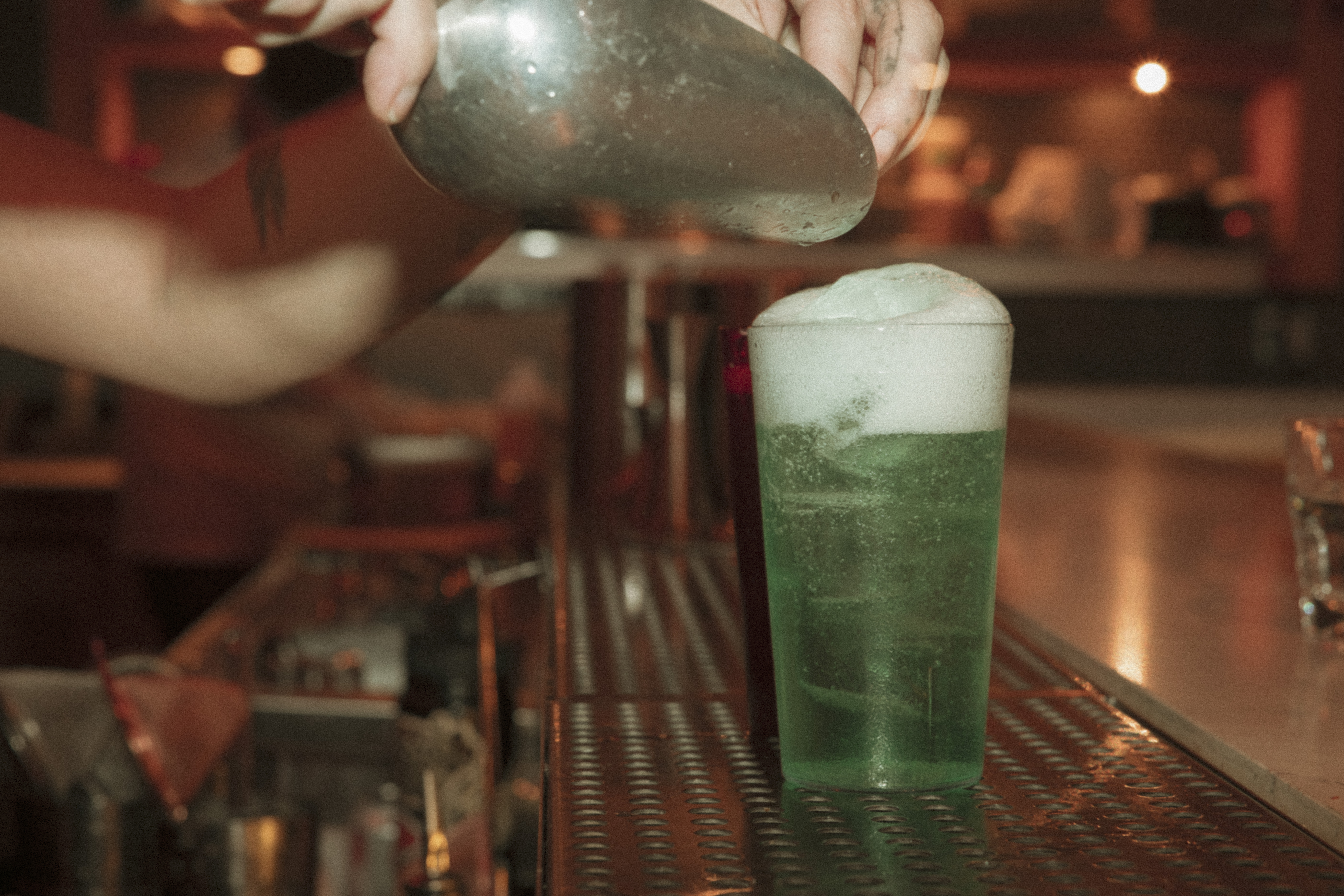 a person pouring a drink into a glass