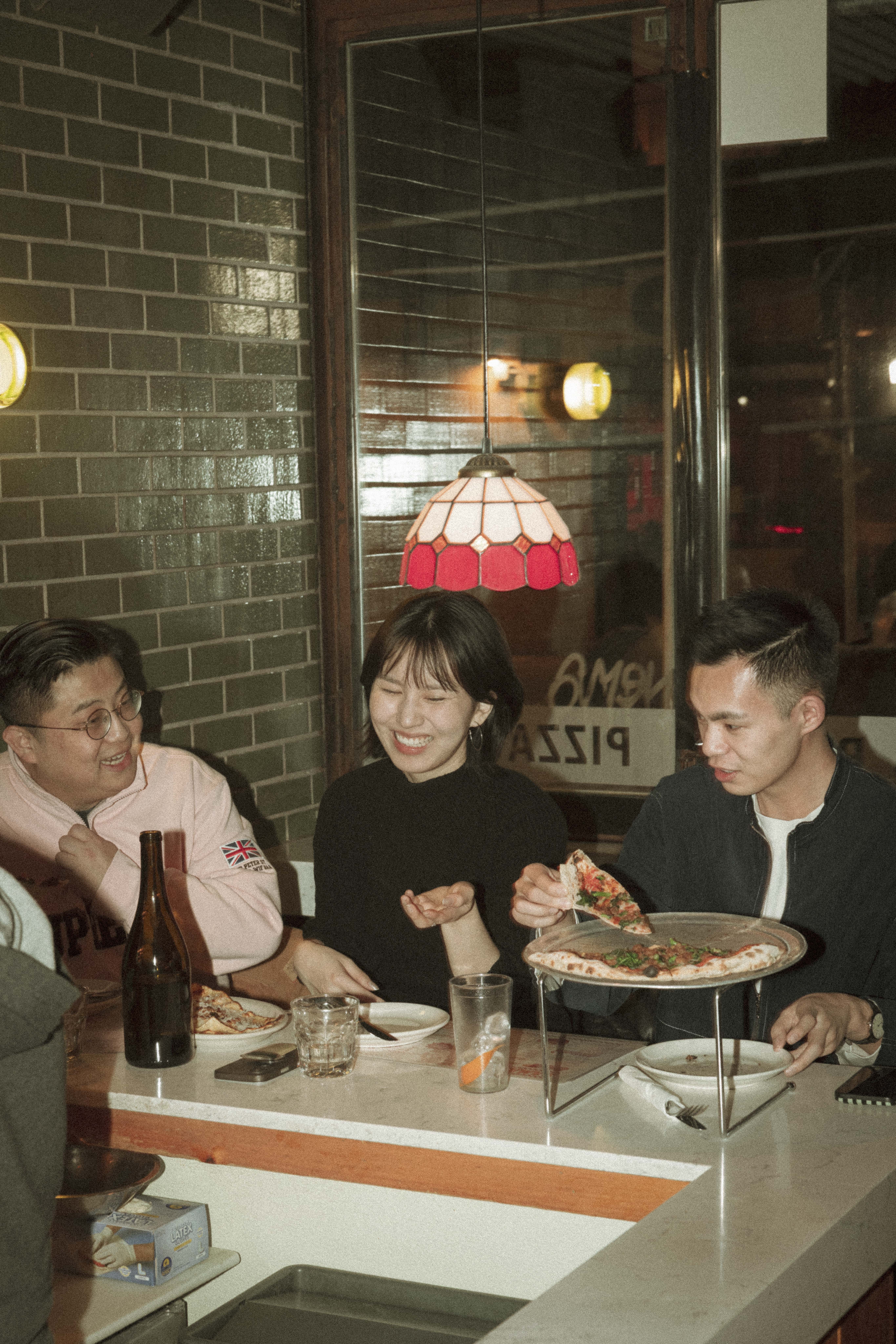 a group of people sitting at a table eating pizza
