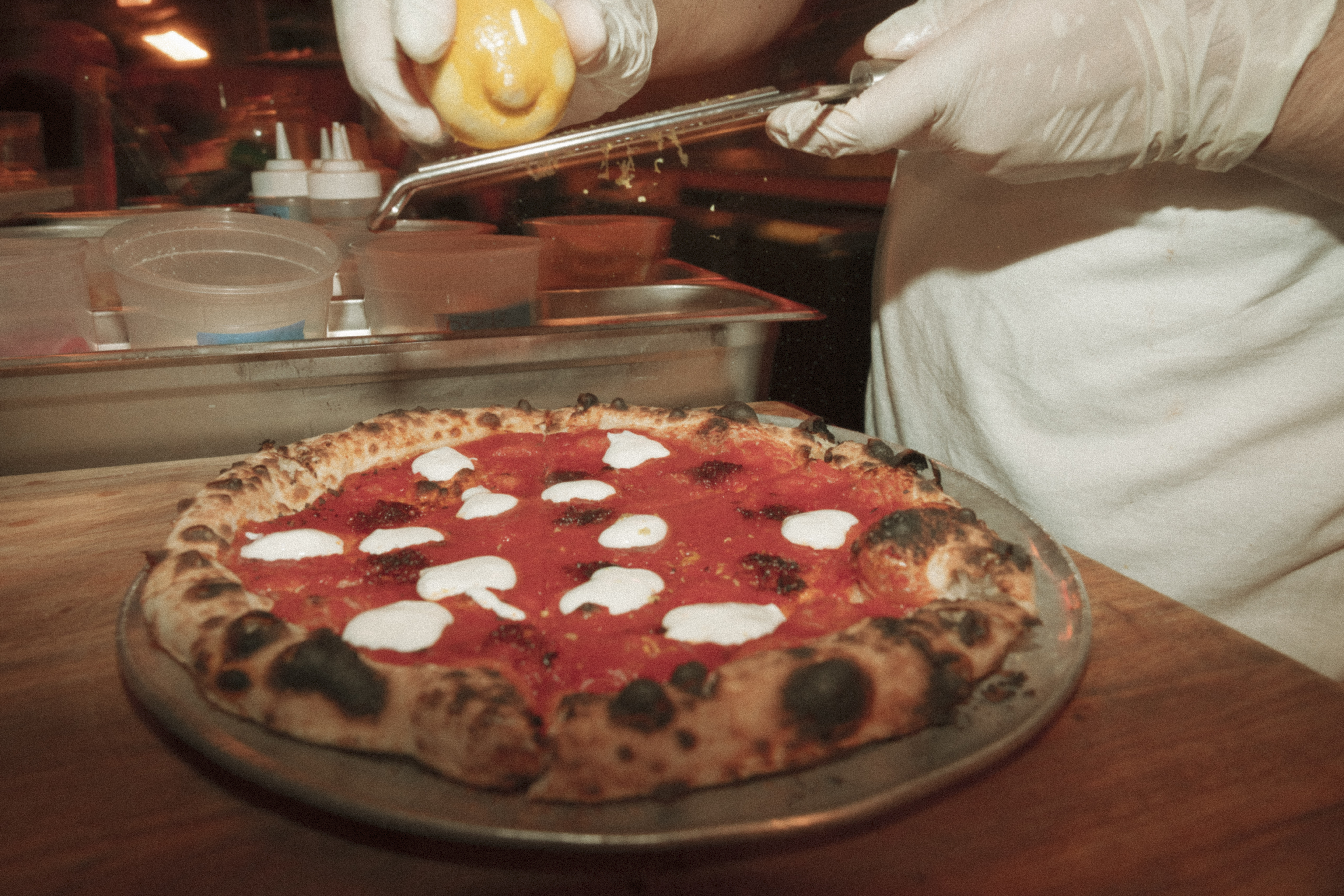 a person squeezing a lemon on a pizza