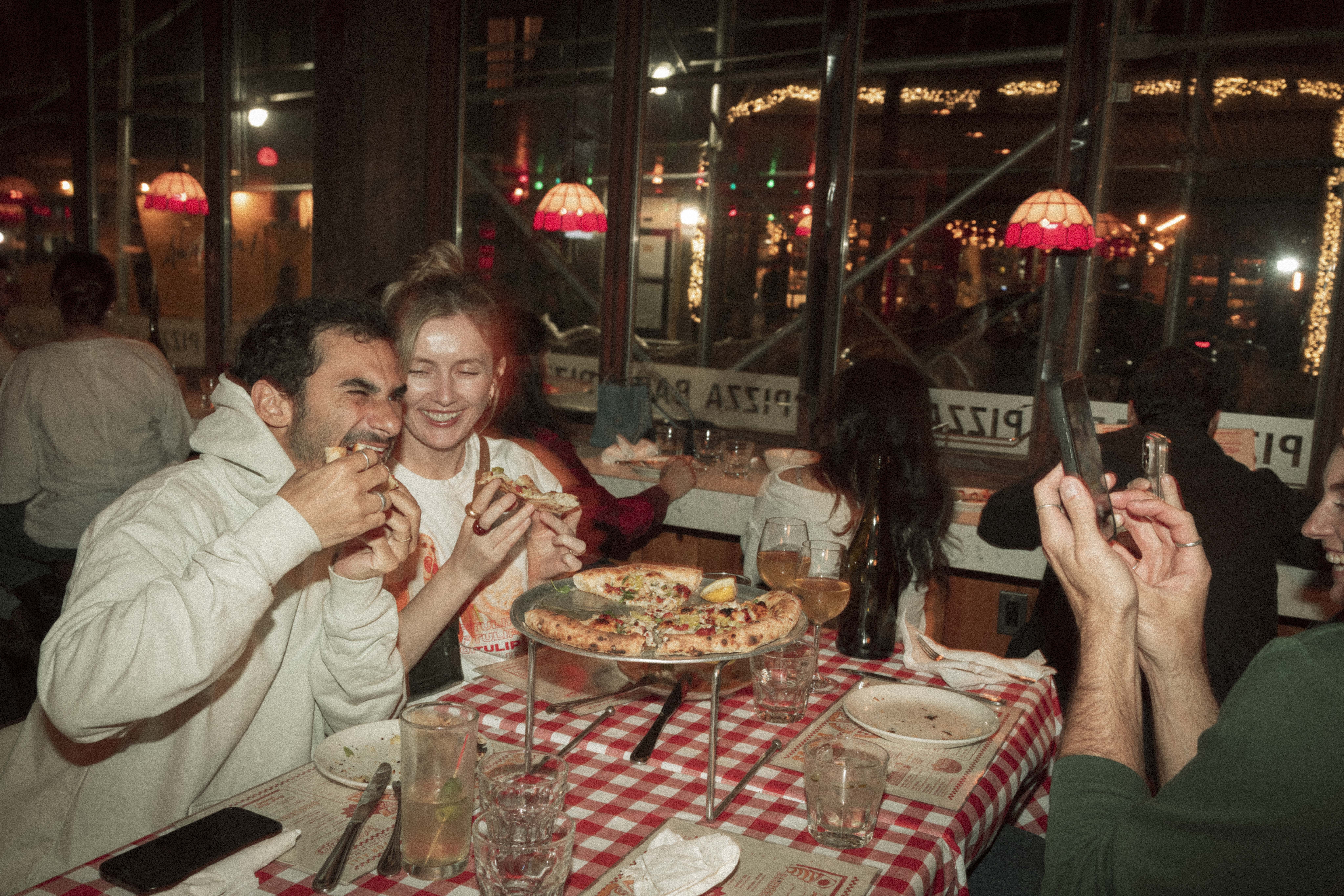 a group of people eating pizza at a restaurant